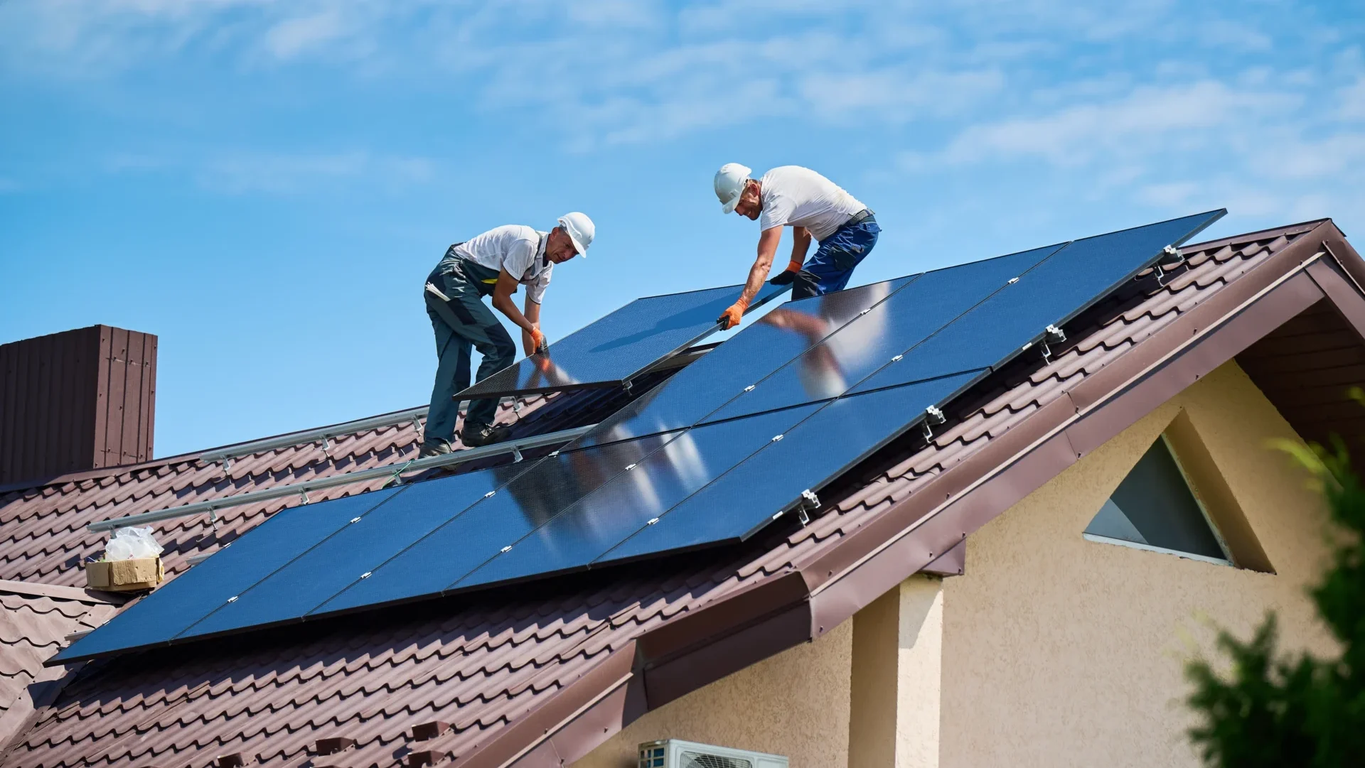 Zwei Männer verlegen Solarpaneele auf einem Dach