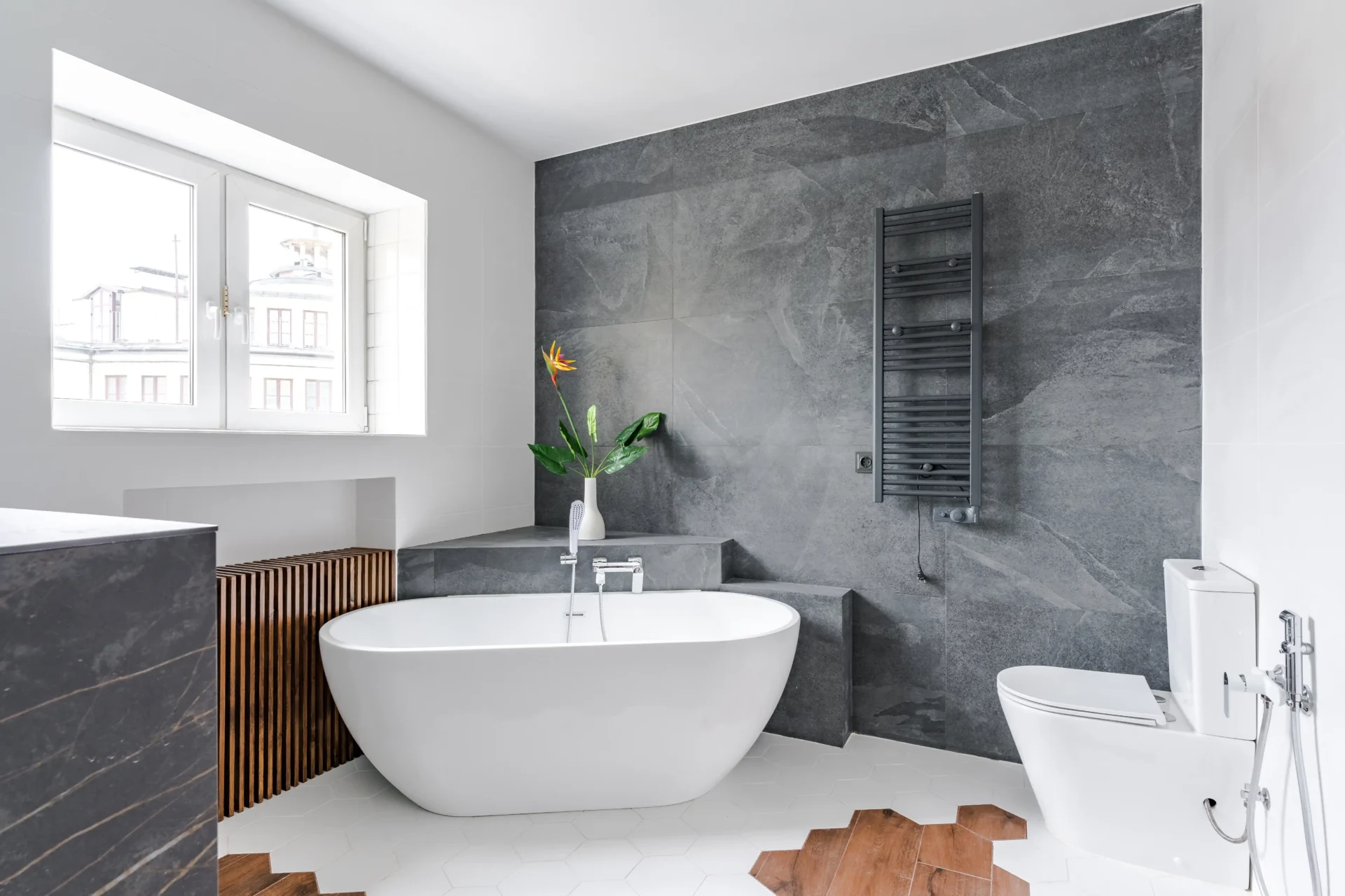 shutterstock_2471000633 Im Innenbereich befindet sich ein modernes kleines Bad mit Fenster zur Straßenseite. Bad mit freistehender Badewanne, WC mit Bidet und Handtuchwärmer.