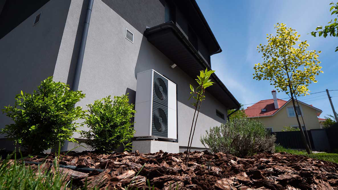 Outdoor-Einheit einer Wärmepumpe gegen die Wand eines modernen Cottage